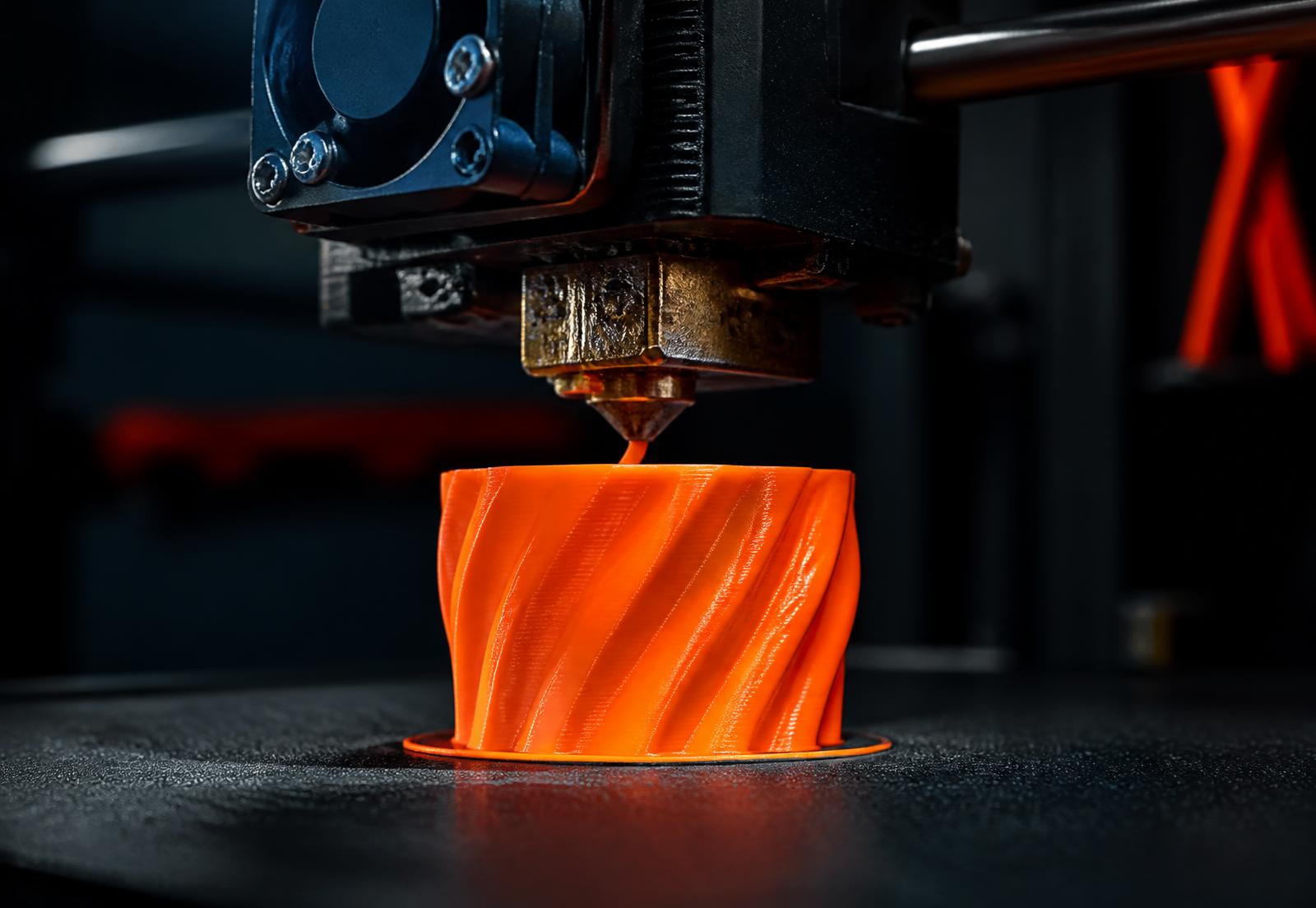 A 3D printer extruding orange filament inside the workshop